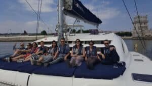 Des personnes assises à l’avant du catamaran avec la Tour de Belém en arrière-plan
