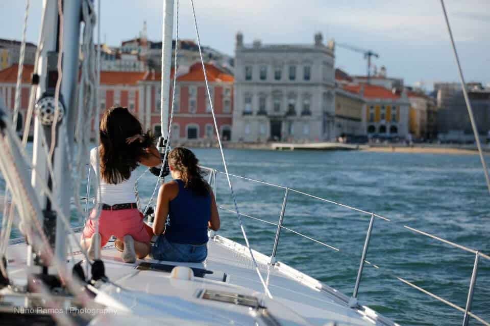 Two women on a sailboat admiring Praça do Comércio
