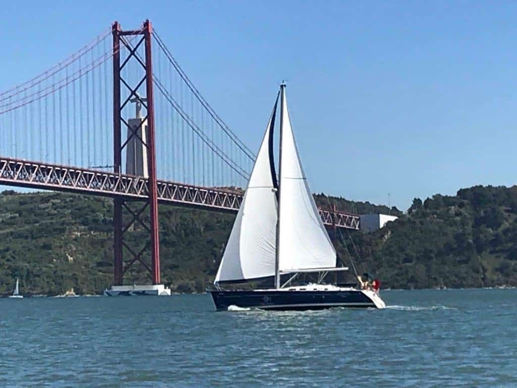 Veleiro a navegar pelo Rio Tejo, perto da Ponte 25 de Abril e do Cristo Rei