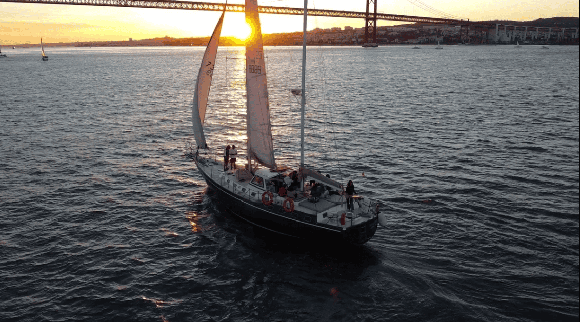 Sailboat at sunset on the Tagus River with a view over Lisbon and the 25 de Abril Bridge