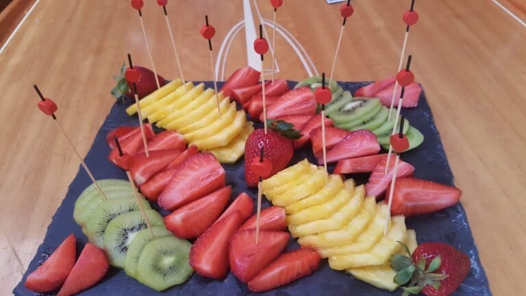 Apresentação de tábuas com frutas variadas como kiwi, morangos, e ananás