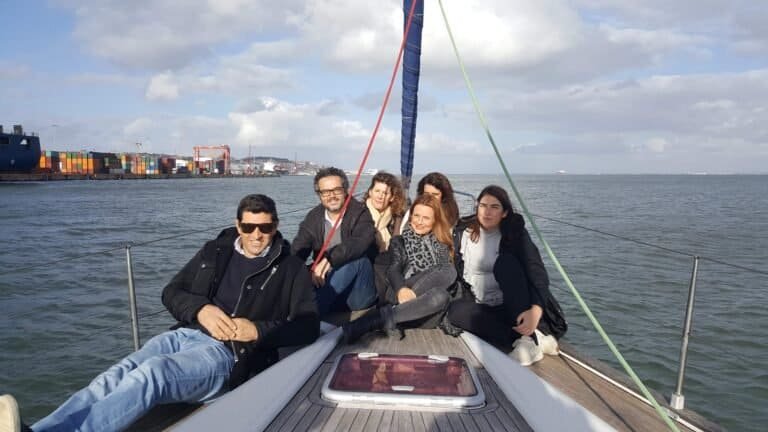 Passeio de barco no rio Tejo ao final de tarde com amigos na proa do barco